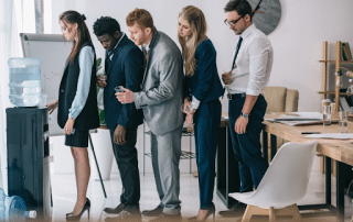 People lining up at a bottled water cooler in a London office