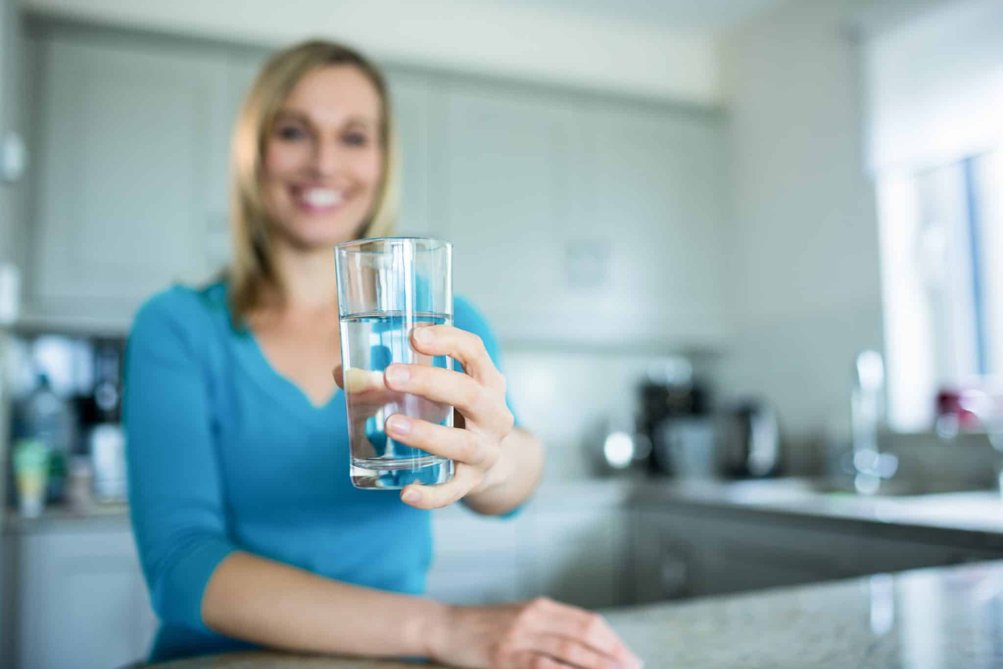 Woman holding fresh and filtered water from a water dispenser, ideal for home or office use.